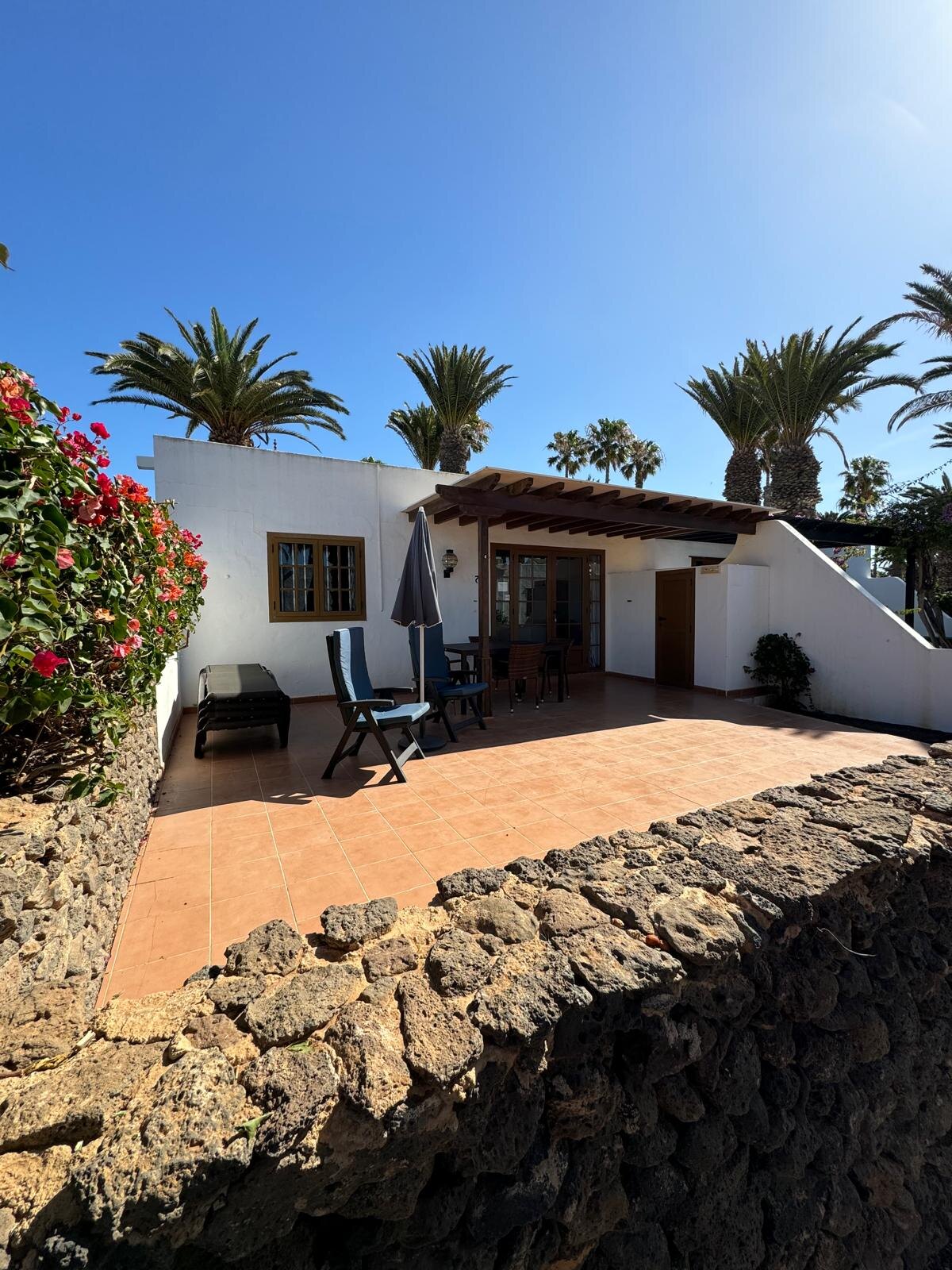 Villa 75 exterior with private terrace, sun lounger and palm trees